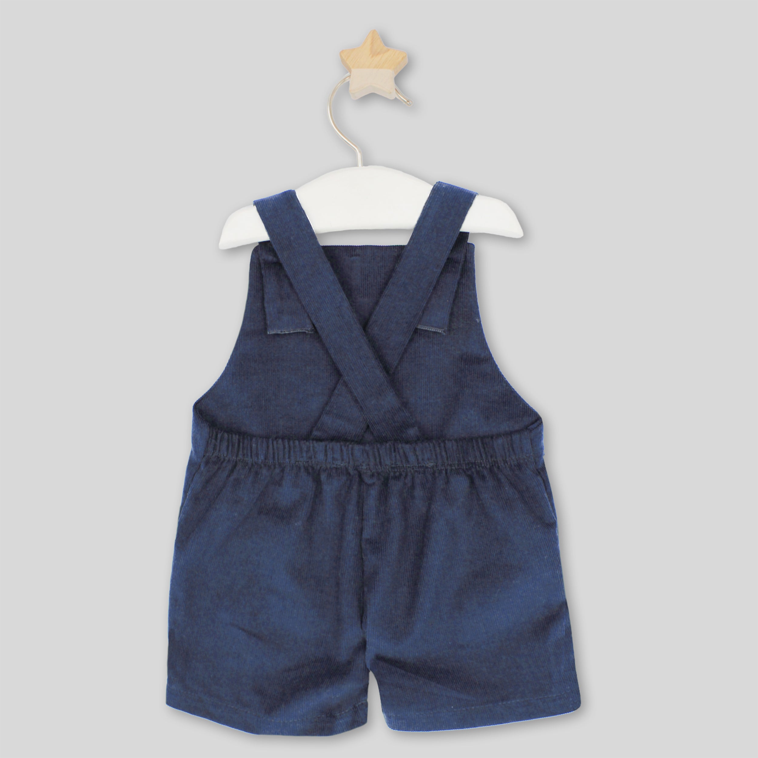 Blue denim overalls on a white hanger against a light gray background
