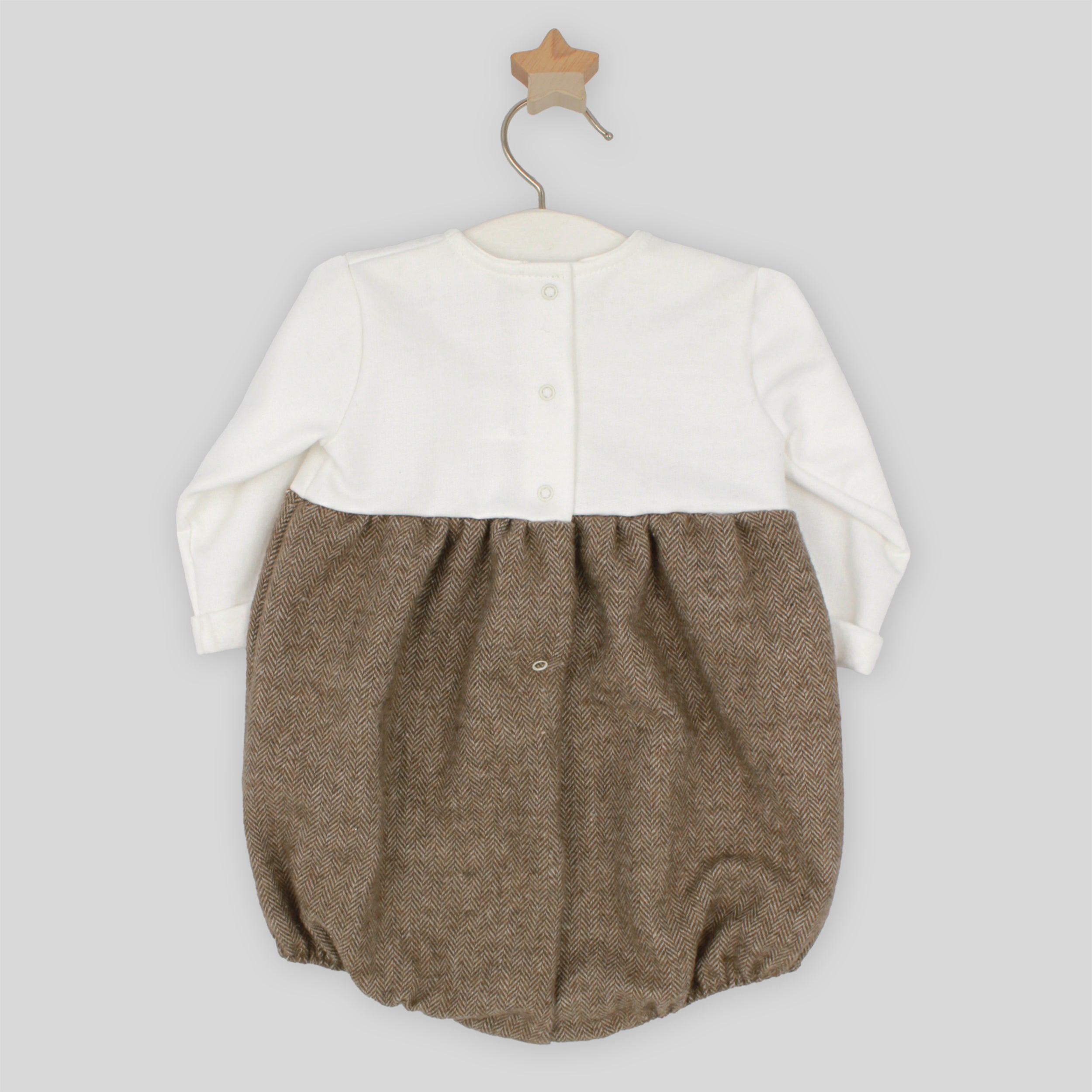 Baby romper with white top and brown bottom on a hanger against a light gray background