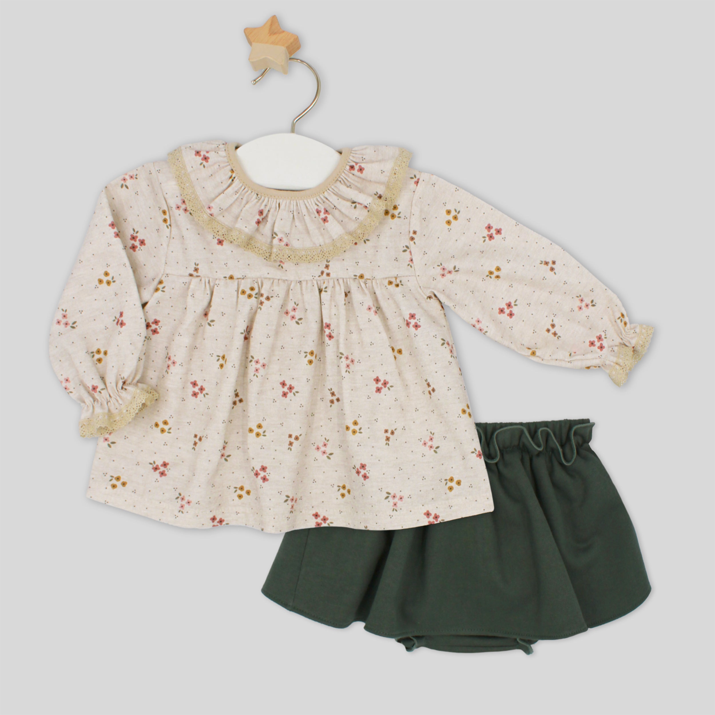 Children's outfit with floral top and green skirt on a light gray background