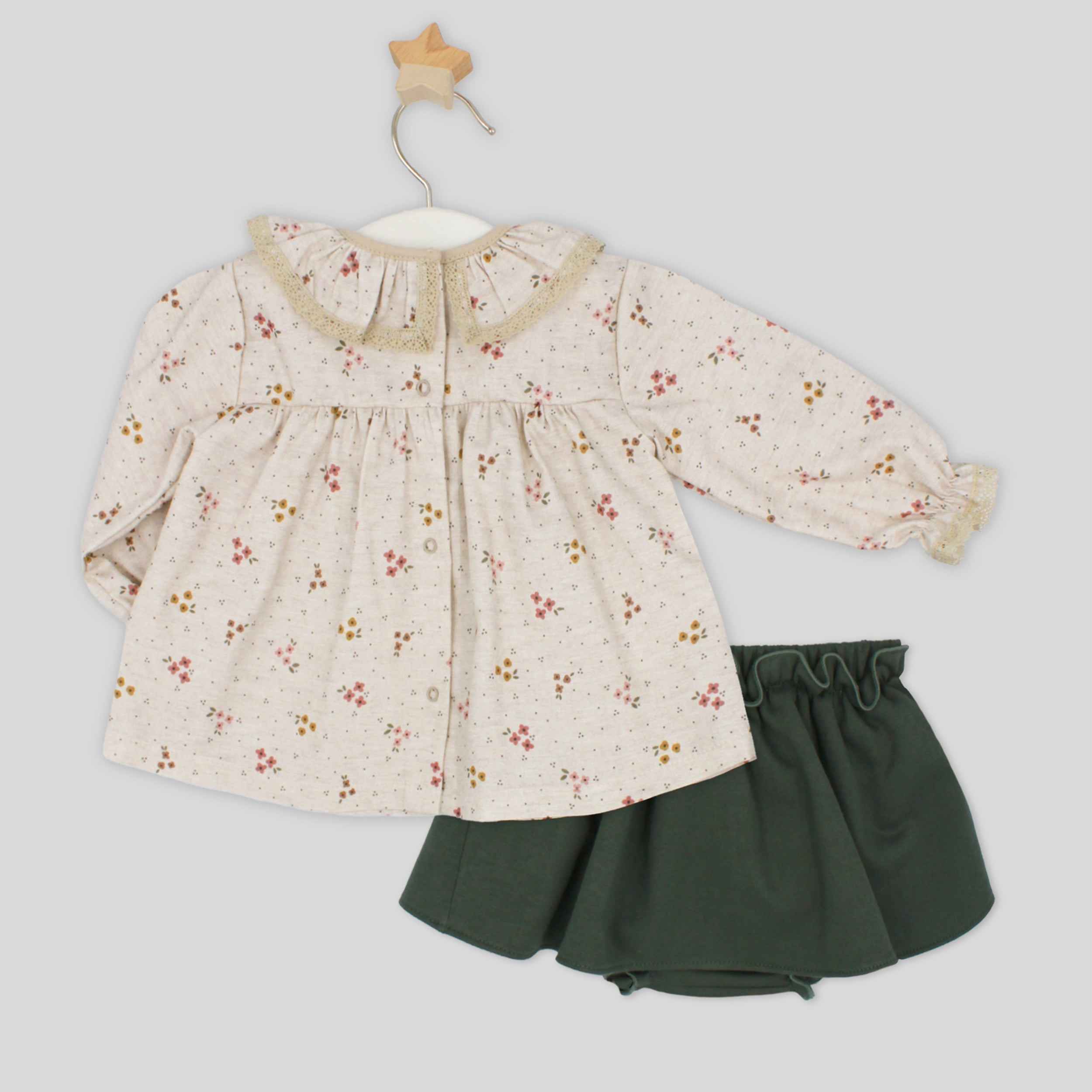 Children's outfit with floral top and green skirt on a light gray background
