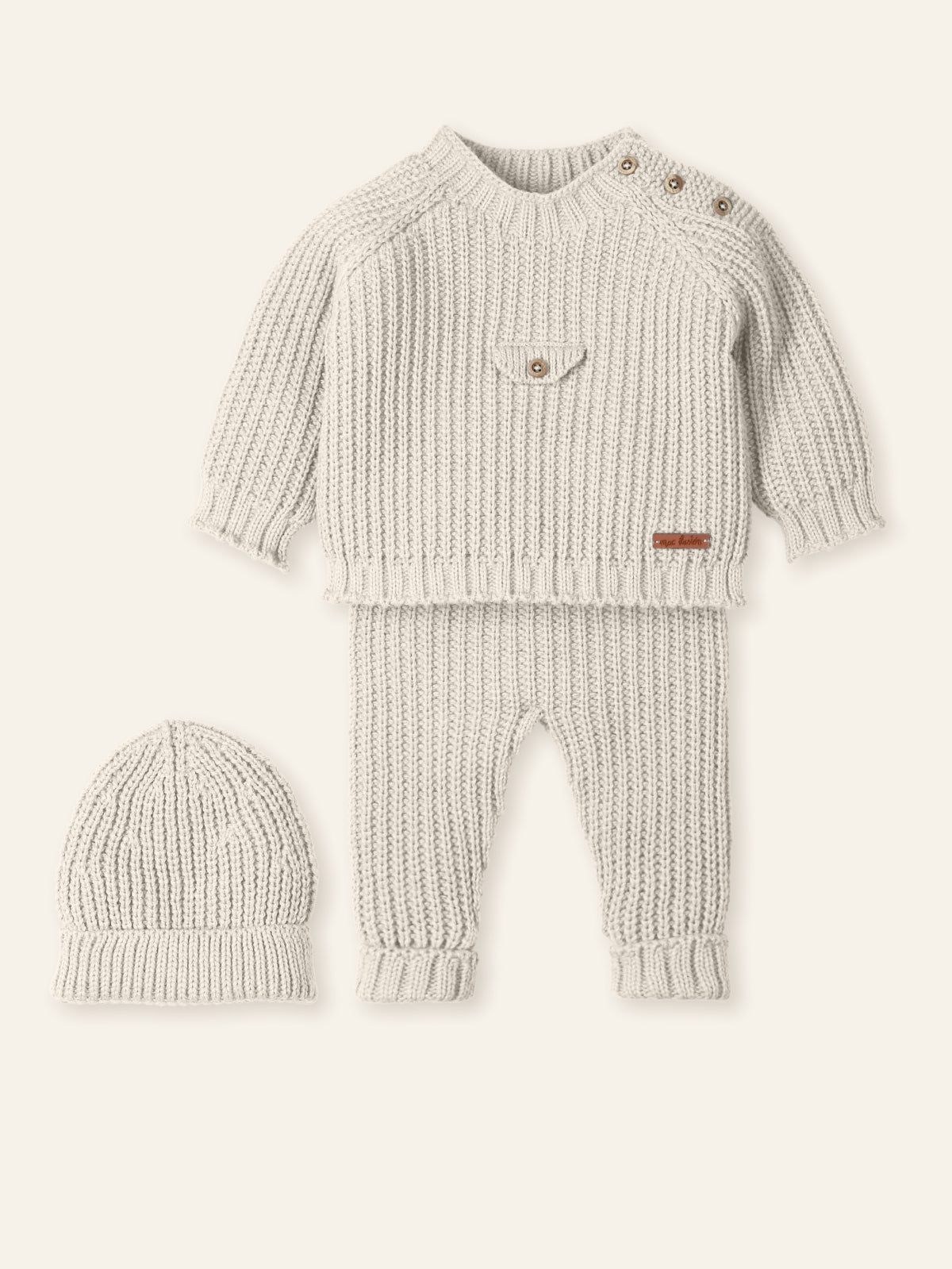 Knitted baby sweater and pants set with matching hat on a white background