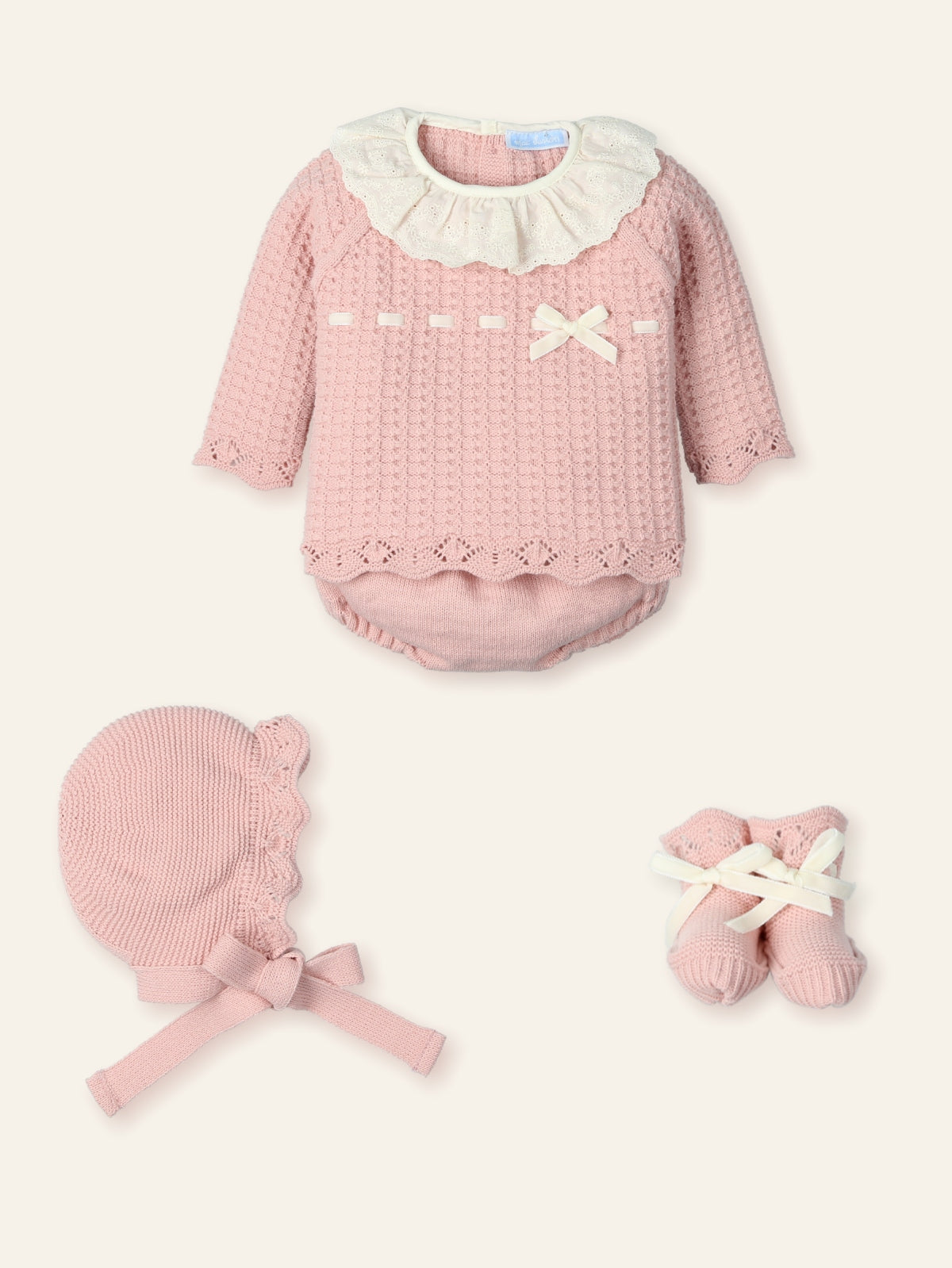 Pink baby outfit with ruffled collar, bonnet, and socks on a white background