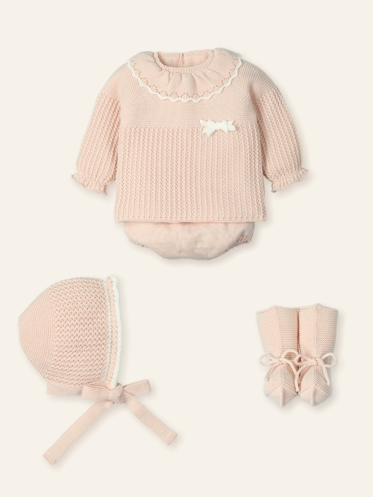 Baby outfit set with pink romper, bonnet, and booties on a white background