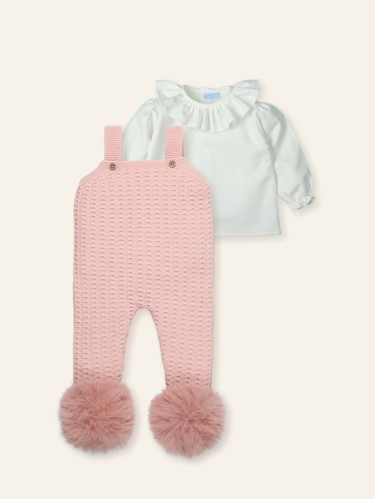 Light blue top and pink knitted romper with pom-poms on a white background