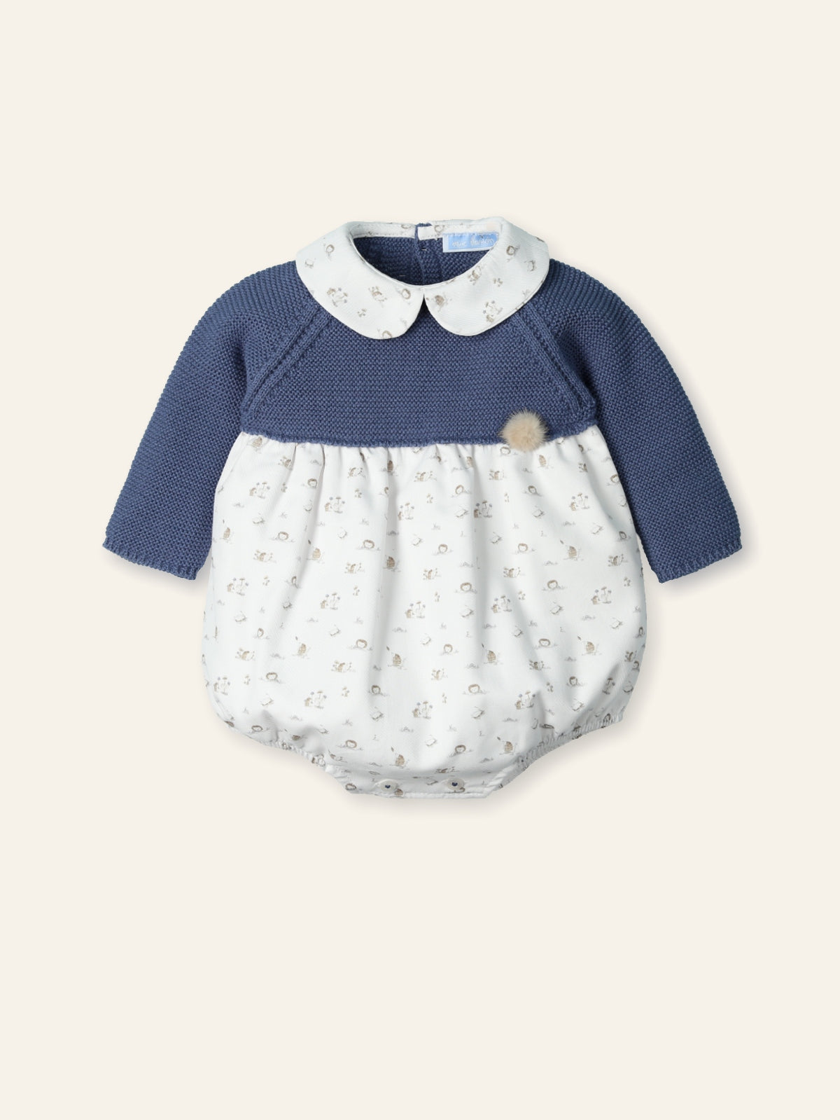 Baby romper with blue top and white bottom on a light beige background
