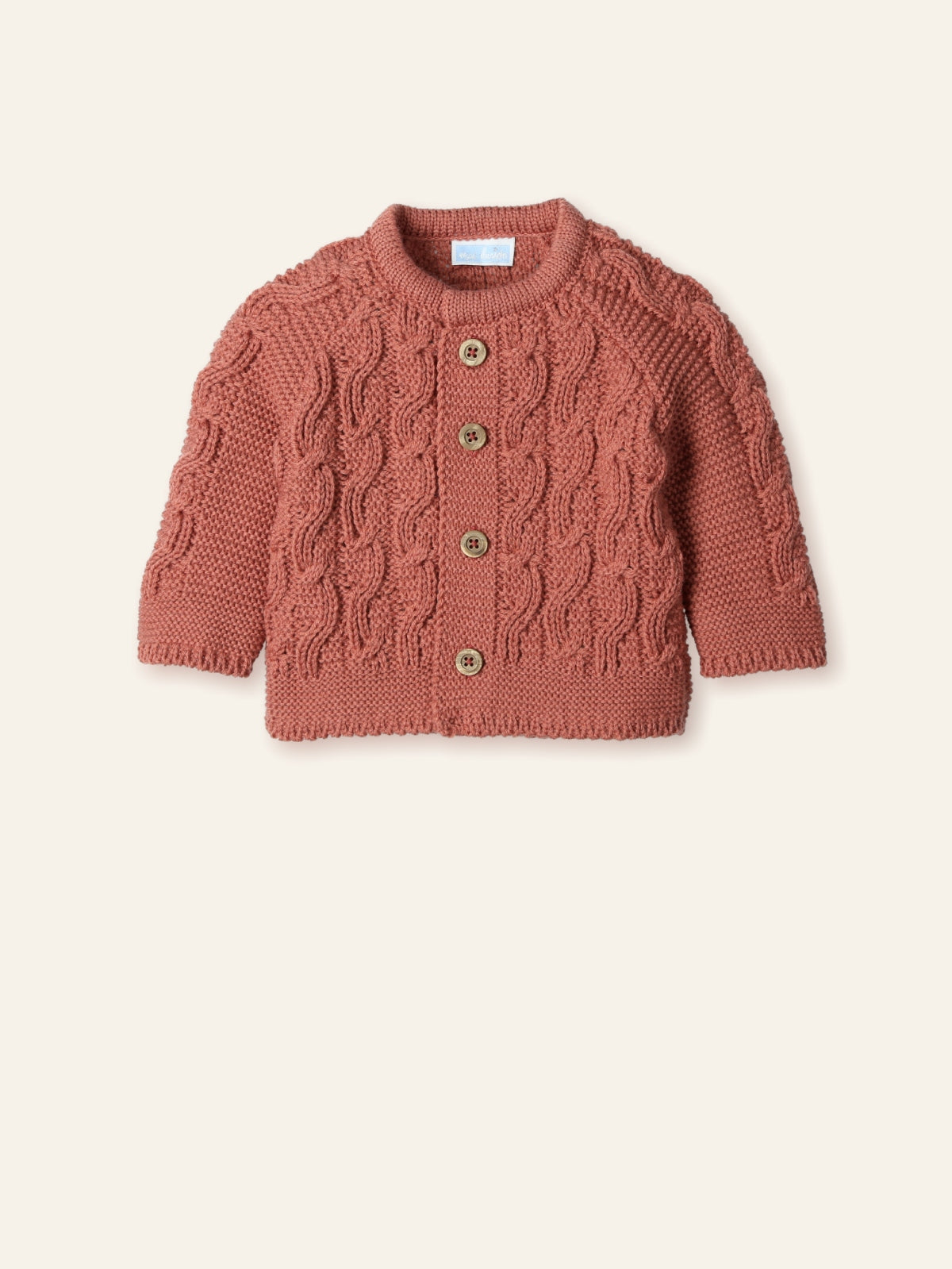 Knitted baby cardigan with cable pattern on a beige background
