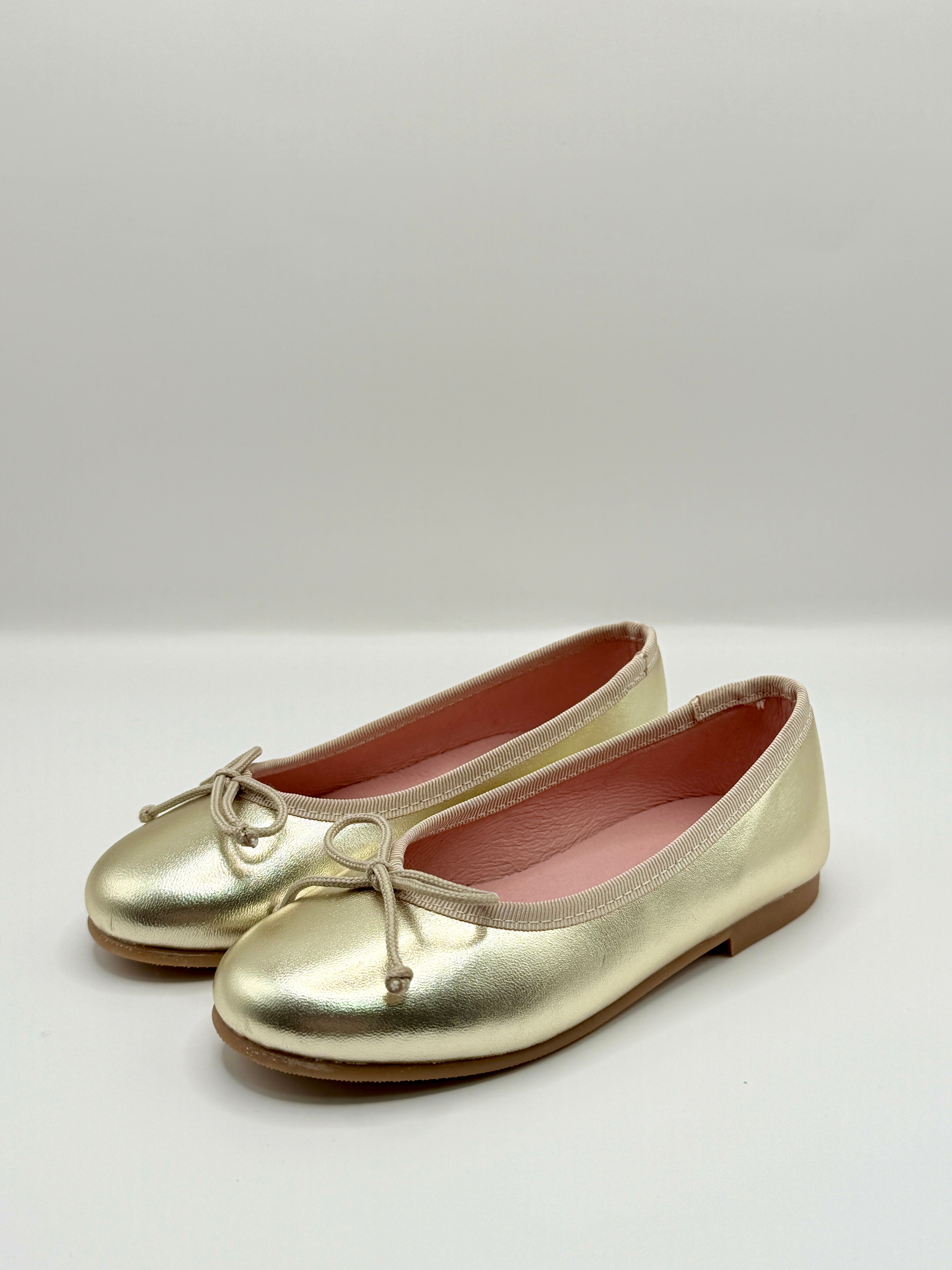 Gold metallic shoes on a white background