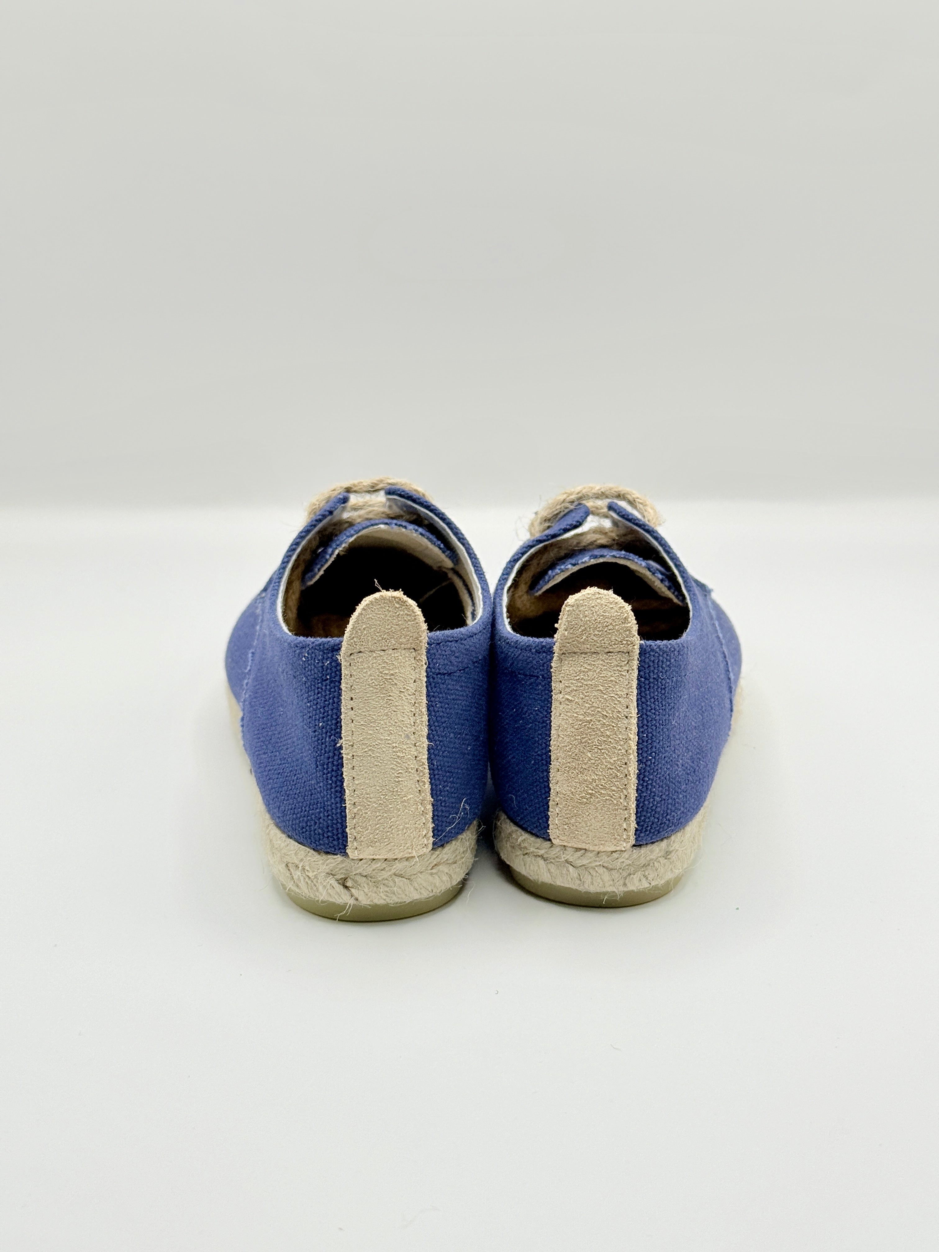 Pair of blue shoes with beige soles on a white background