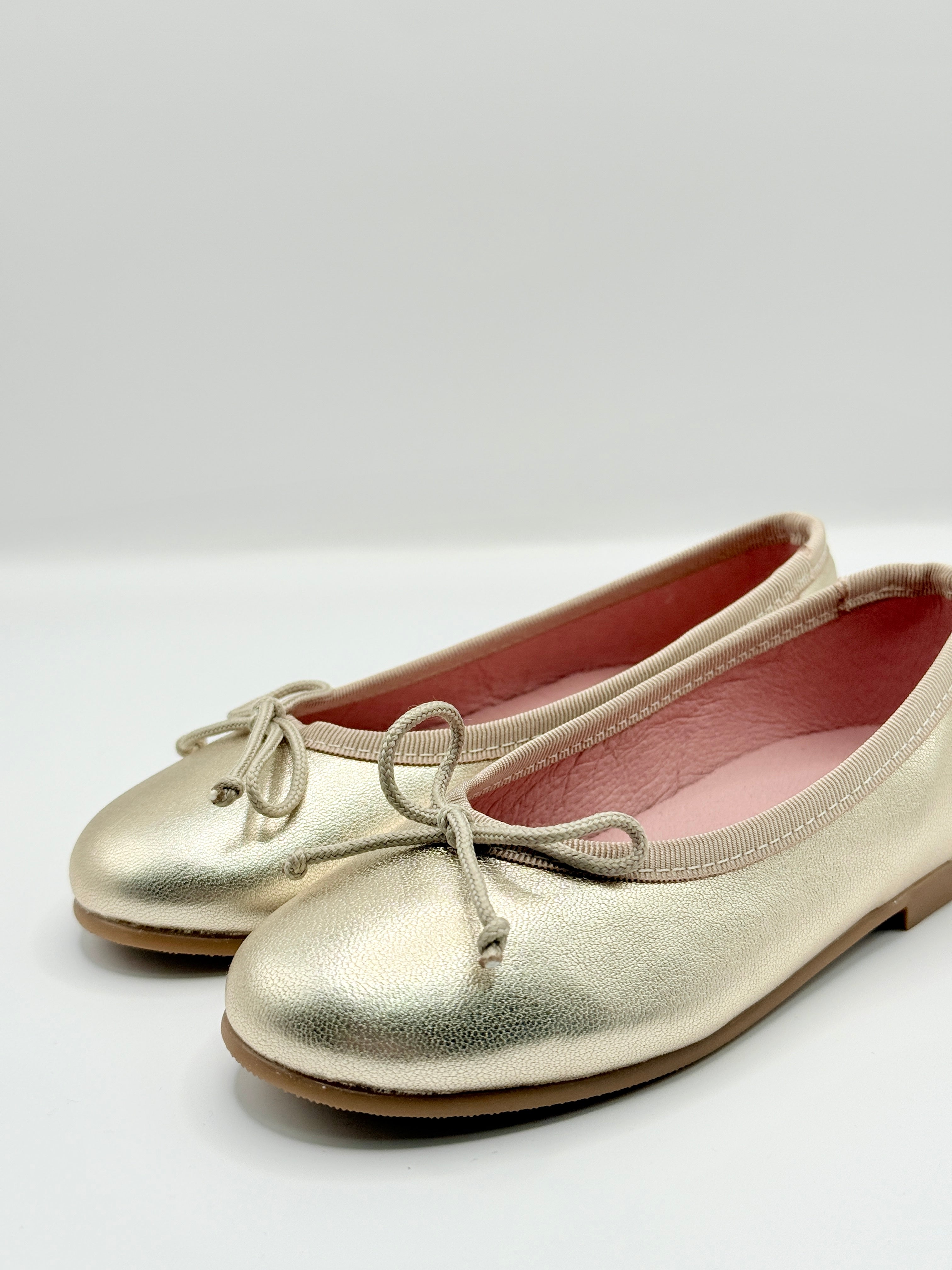 Gold ballet flats on a white background