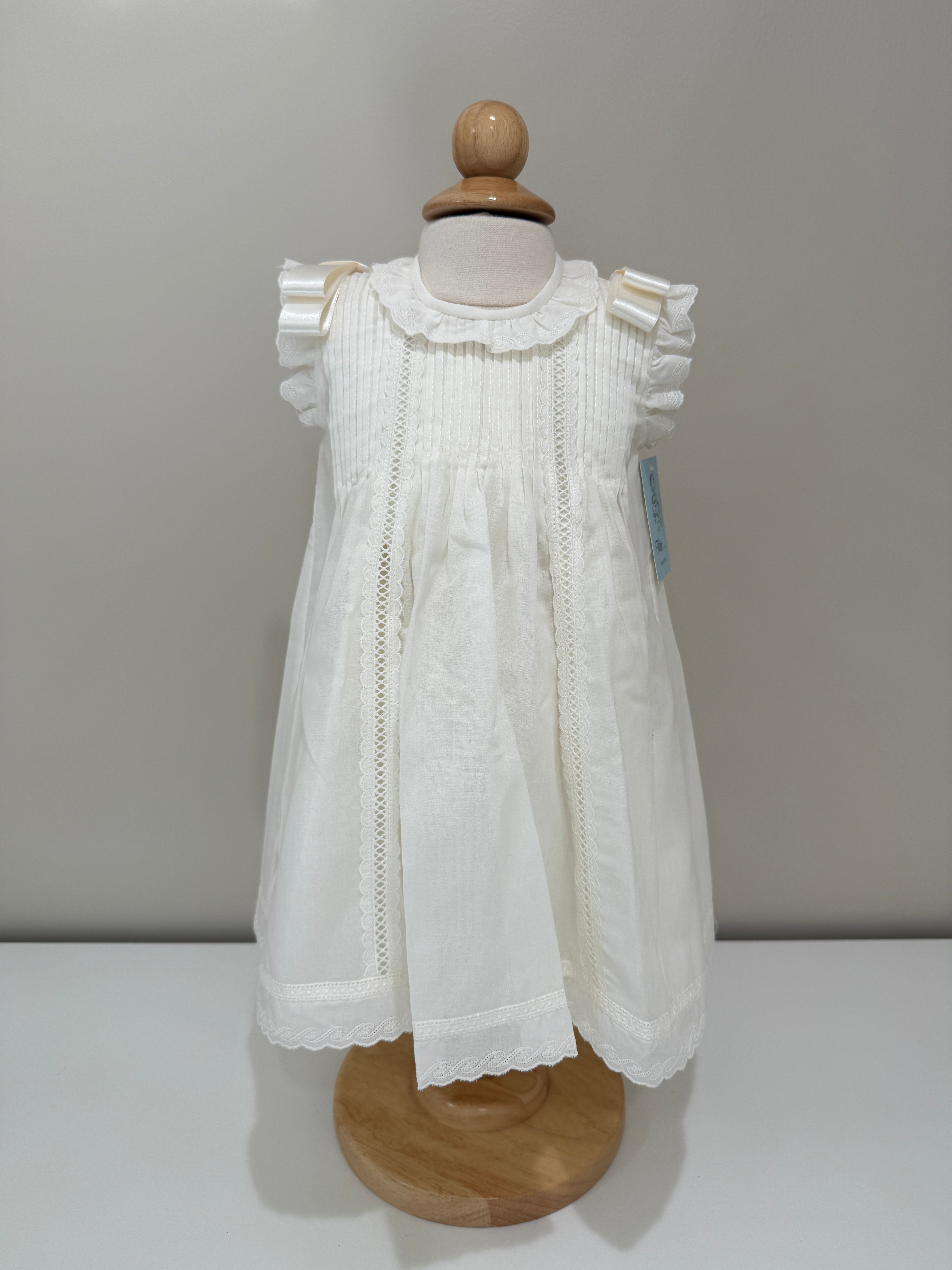 White lace dress on a mannequin with wooden head and shoulders against a plain background