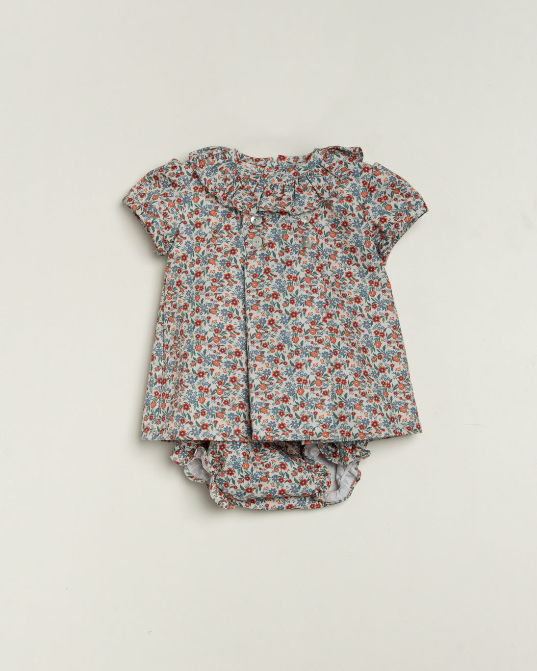 Floral baby outfit with top and bloomers on a light gray background