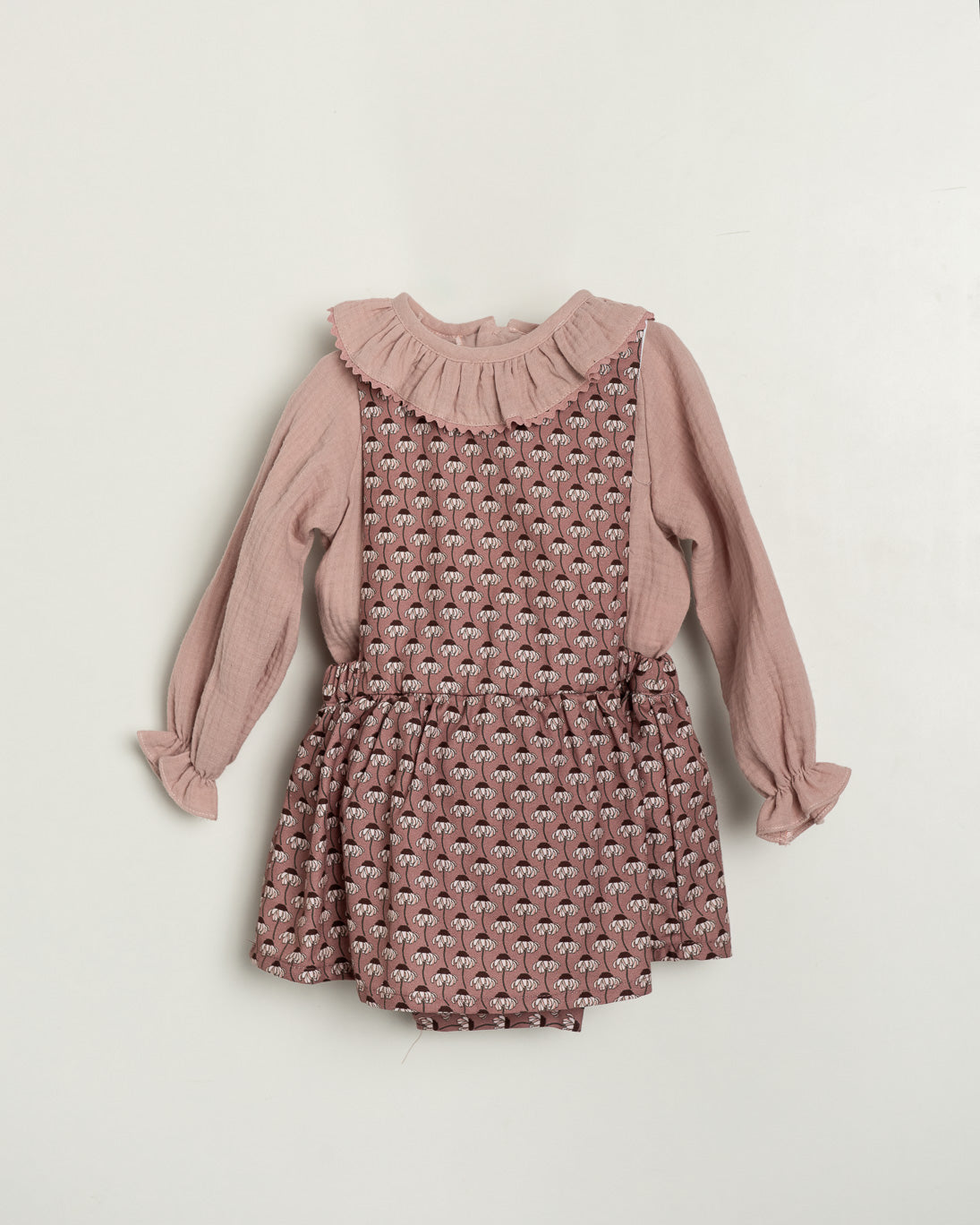 Pink patterned romper with long-sleeve top on a light beige background