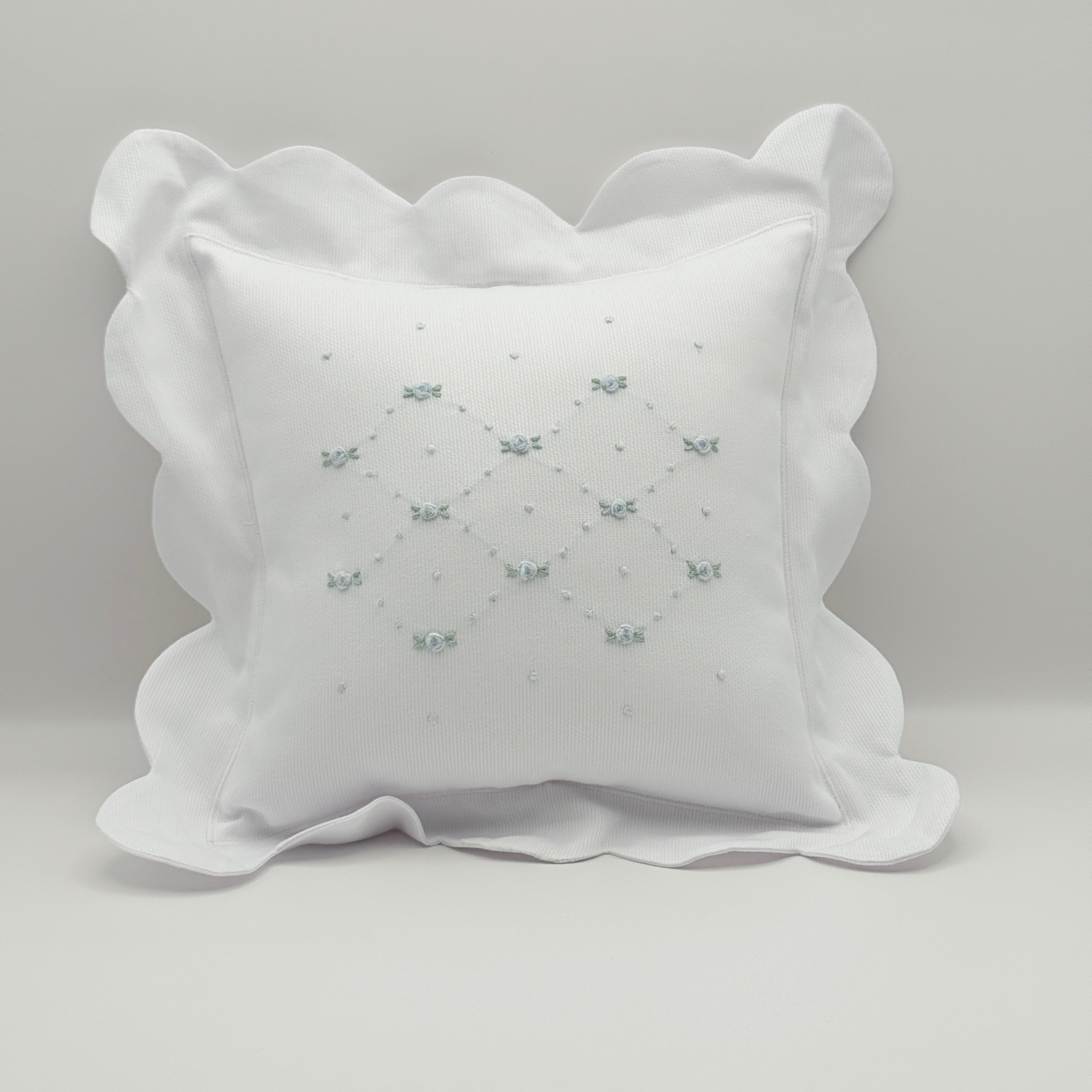 White decorative pillow with ruffled edges on a light gray background