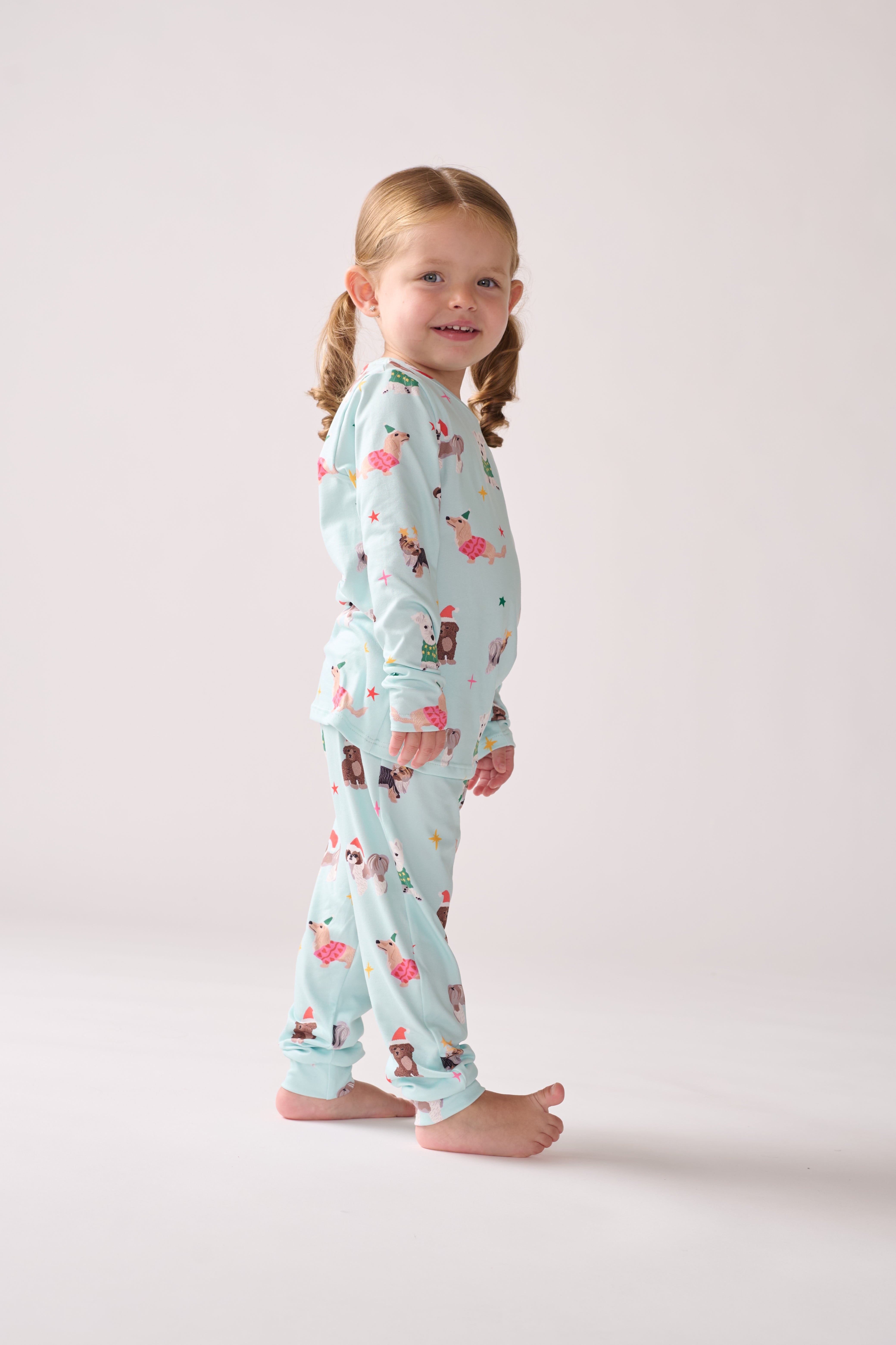Child wearing a light blue pajama set with animal prints on a plain background