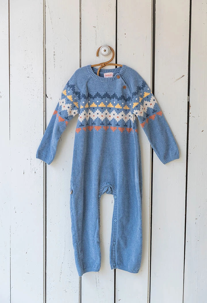 Blue knitted baby romper with a pattern on a wooden background